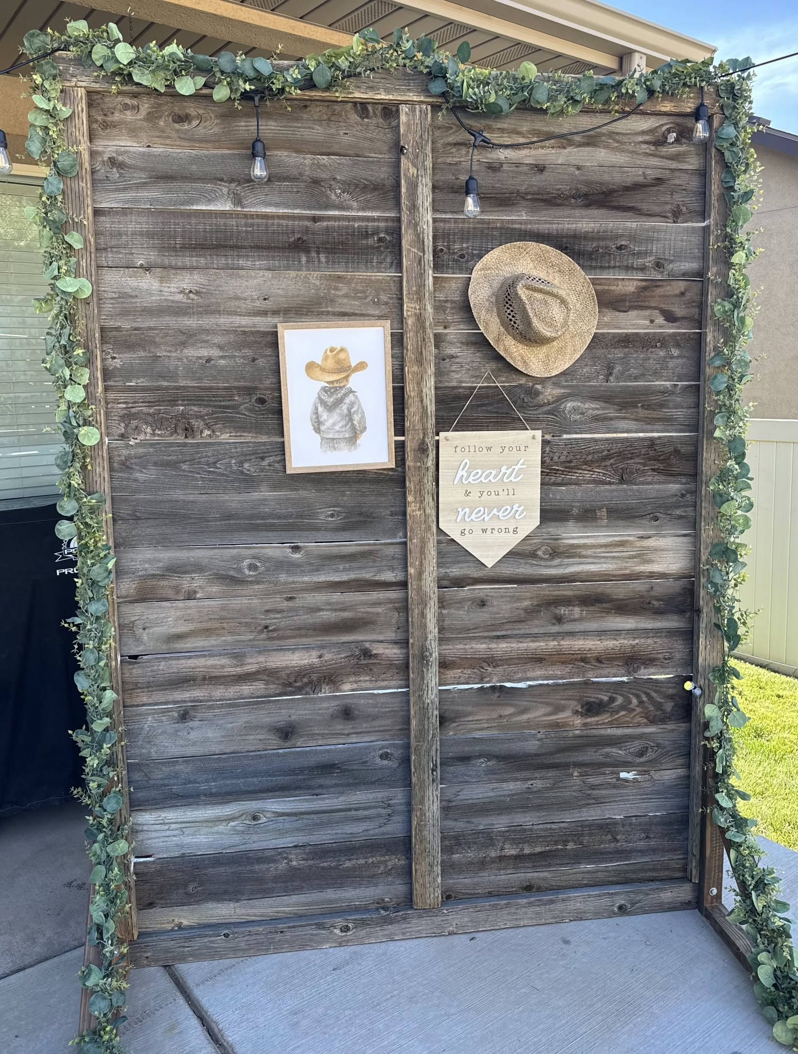 The same barnwood backdrop dressed with eucalyptus garland and bistro lights