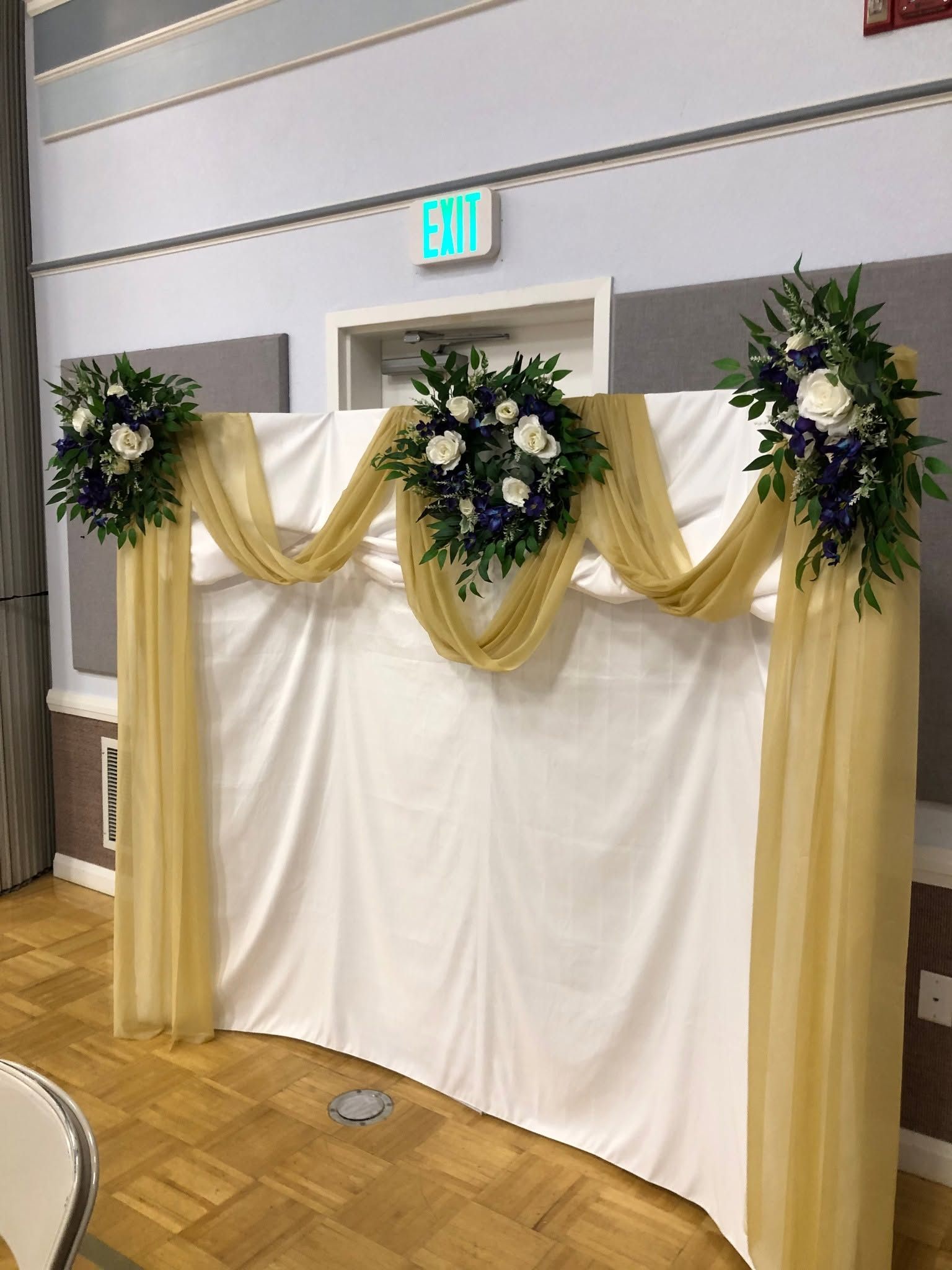 Champagne chiffon draped backdrop with ivory and plum floral swags