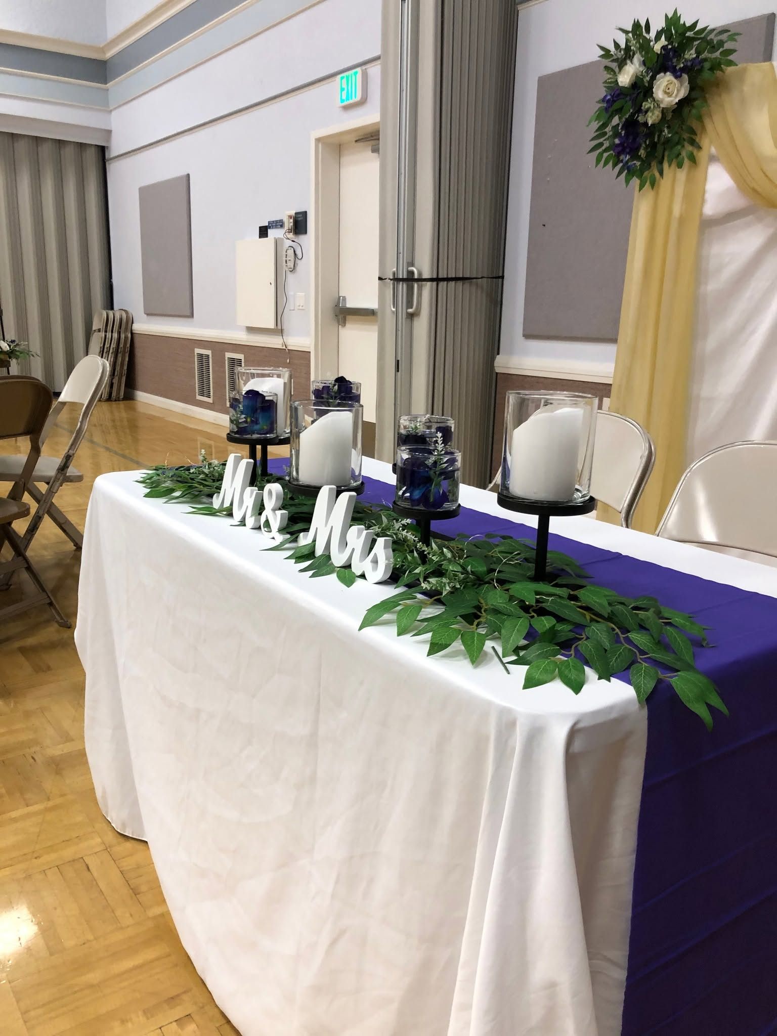 Wedding head table with Mr and Mrs lettering, greenery garland and candle hurricanes