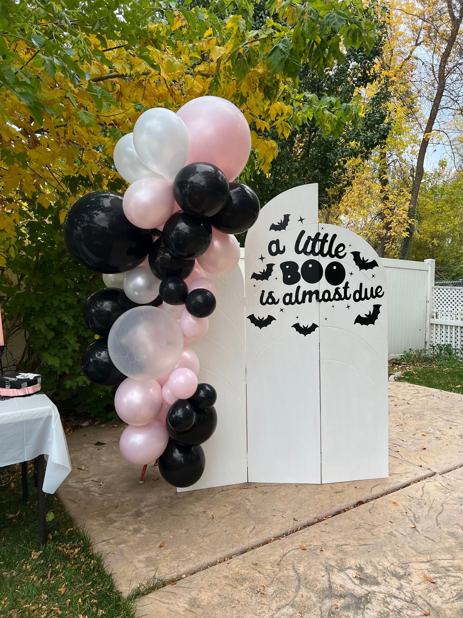 Halloween baby shower arched backdrop with black and pink balloon garland