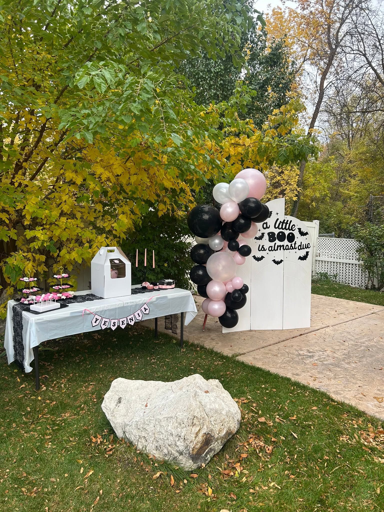 Halloween themed baby shower set up in a backyard with dessert table