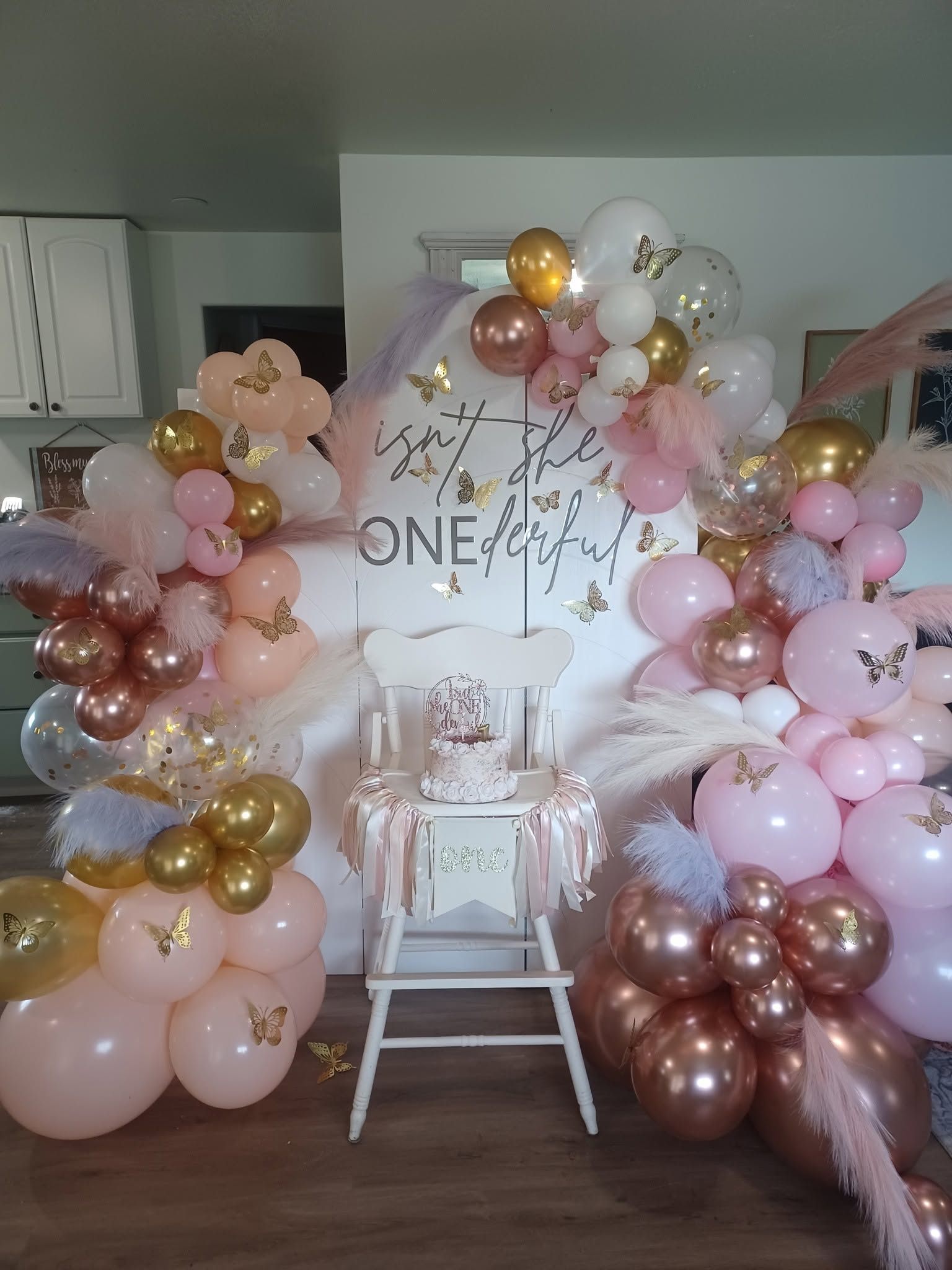 Blush and gold organic balloon garland installed around an arched backdrop