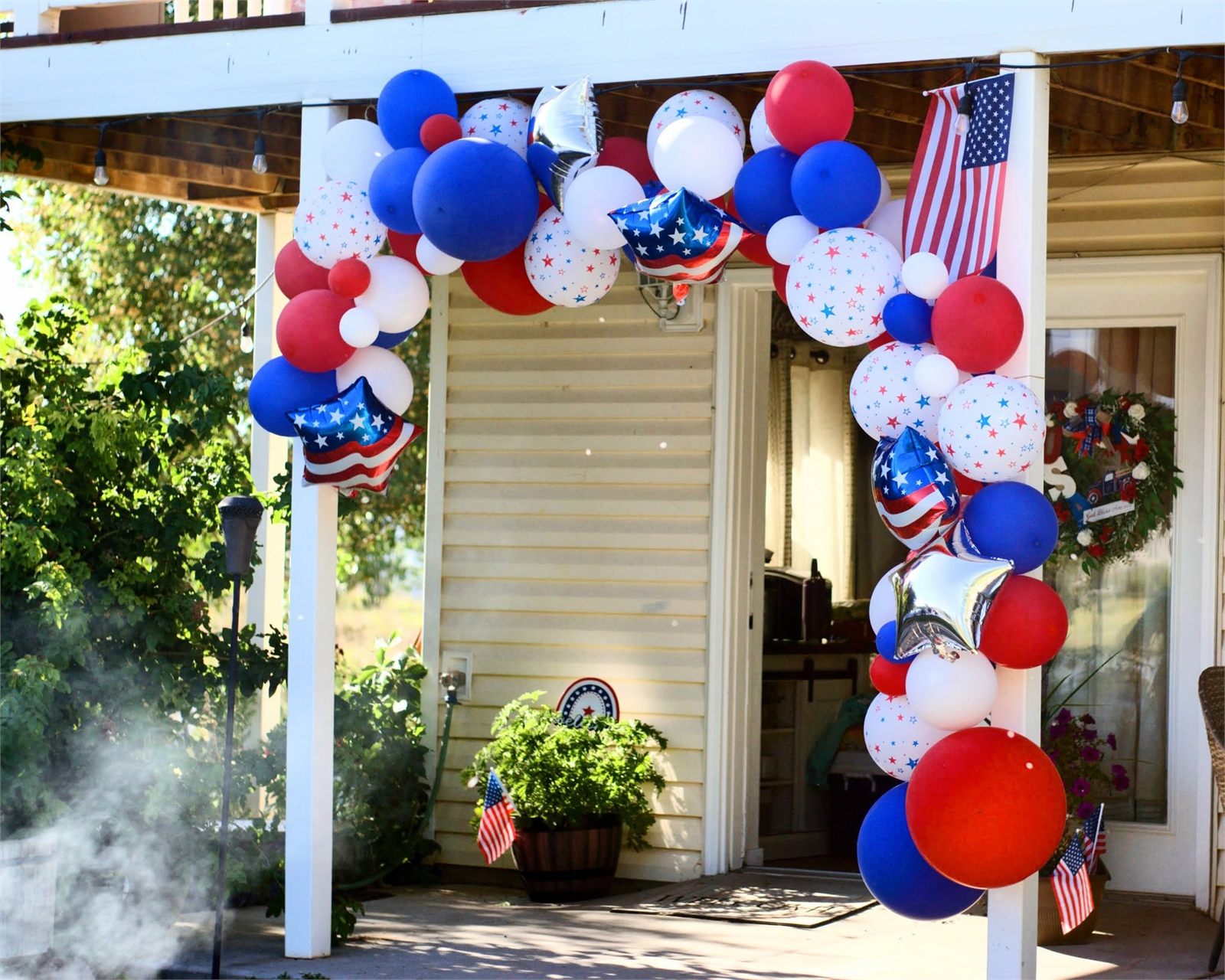 Red white and blue Fourth of July balloon garland arching over a porch entrance
